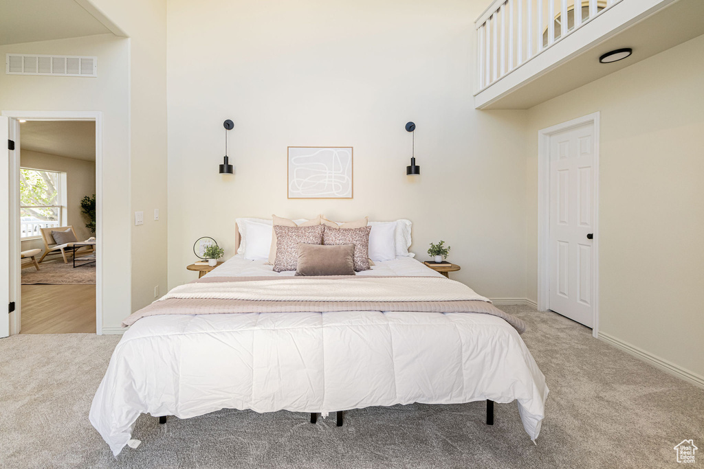 Bedroom featuring a high ceiling, light colored carpet, baseboards, and visible vents