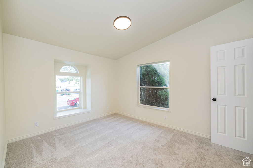 Carpeted spare room with baseboards and lofted ceiling