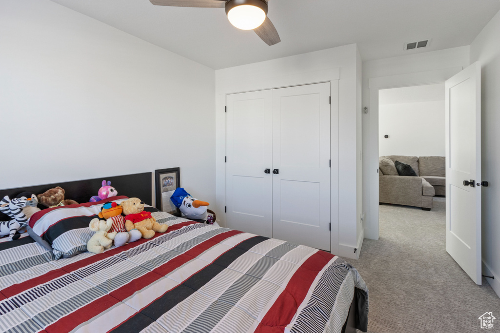 Carpeted bedroom featuring visible vents, ceiling fan, and a closet