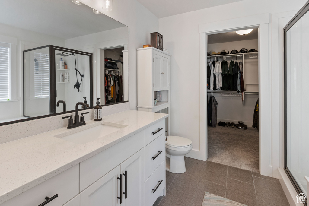 Bathroom featuring vanity, a spacious closet, toilet, and a shower stall