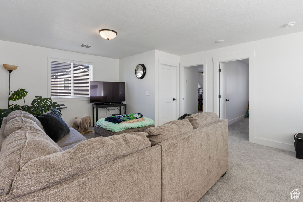 Living area featuring visible vents, baseboards, and light colored carpet