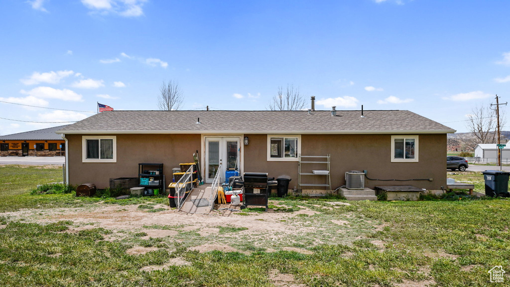 Back of property featuring central air condition unit, a chimney, roof with shingles, stucco siding, and french doors