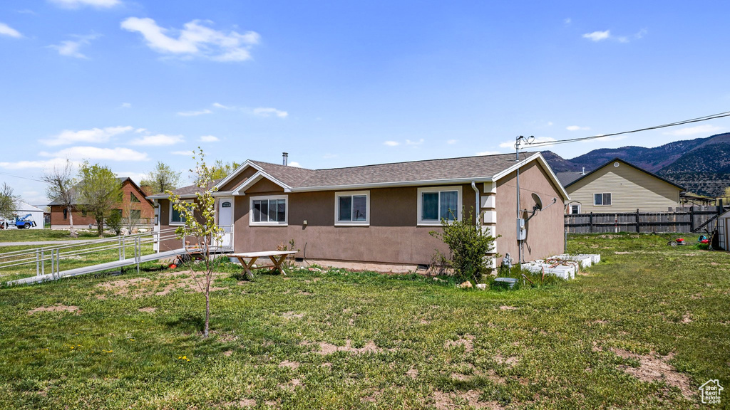 Ranch-style home with a mountain view, a front lawn, a fenced backyard, and stucco siding