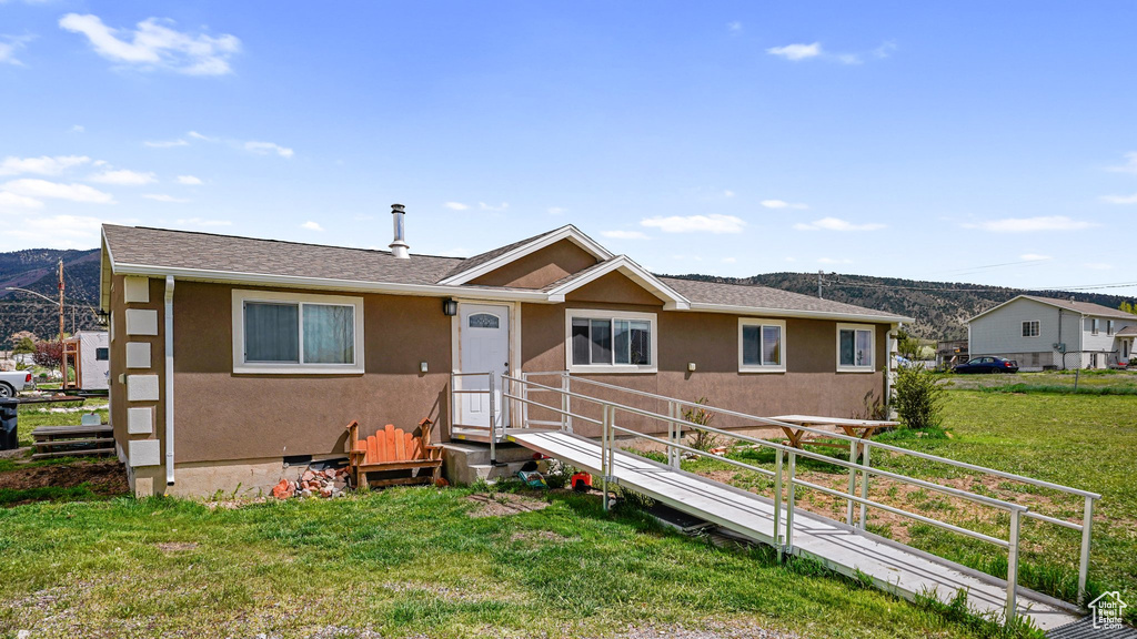 View of front of property with a front lawn, stucco siding, and a mountain view