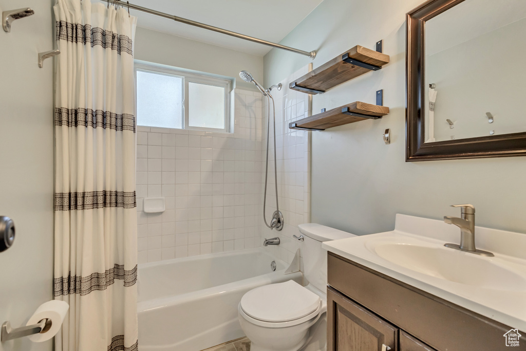 Bathroom with toilet, shower / bath combo, and vanity