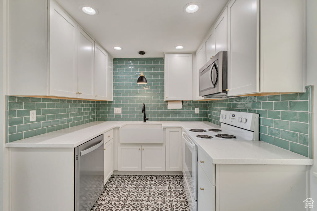 Kitchen featuring a sink, appliances with stainless steel finishes, white cabinets, and light countertops
