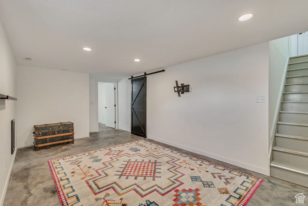 Finished basement with recessed lighting, baseboards, stairs, and a barn door