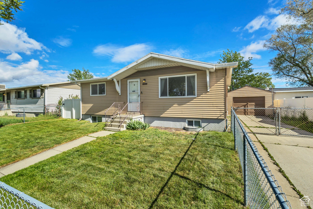 View of front of home with fence, an outbuilding, a front yard, and a garage