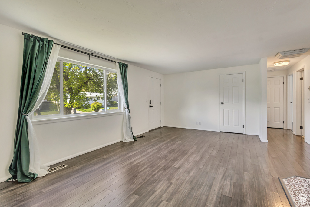 Unfurnished living room with baseboards, wood finished floors, and visible vents