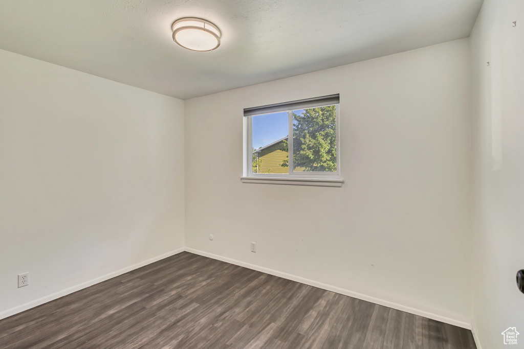 Empty room with baseboards and dark wood finished floors