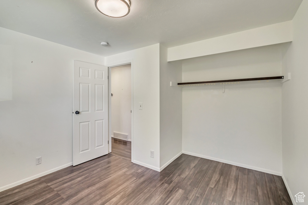 Unfurnished bedroom with baseboards, a closet, wood finished floors, and visible vents
