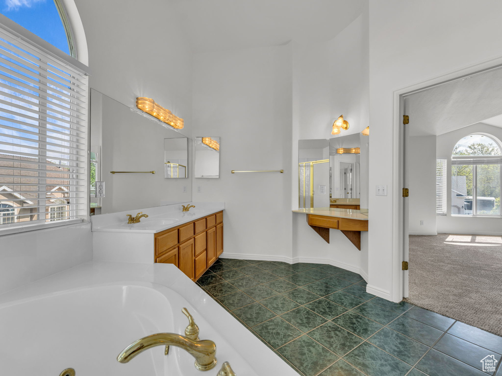 Bathroom with a garden tub, a sink, a towering ceiling, and tile patterned flooring