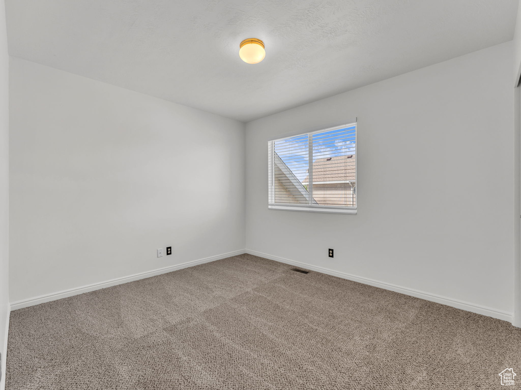 Empty room with carpet flooring, baseboards, and visible vents