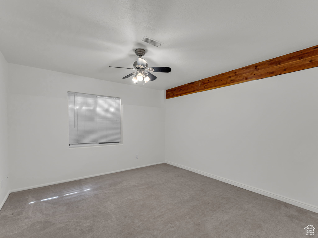 Spare room featuring visible vents, carpet flooring, baseboards, and a ceiling fan