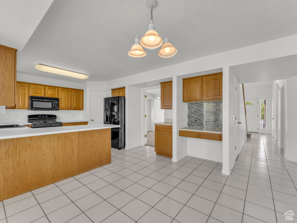 Kitchen with a peninsula, light countertops, light tile patterned floors, backsplash, and black appliances