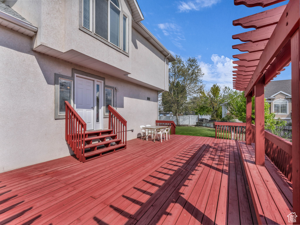 Wooden terrace featuring a yard, fence, outdoor dining space, and entry steps