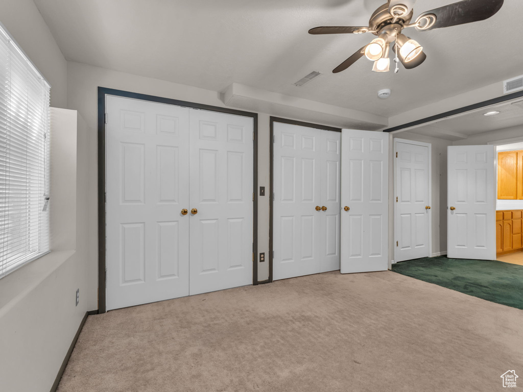 Unfurnished bedroom with a ceiling fan, visible vents, baseboards, multiple closets, and carpet