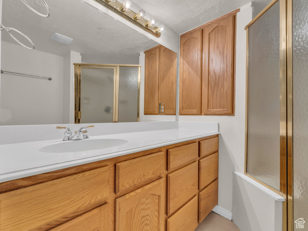 Bathroom featuring vanity, tile patterned flooring, and a shower stall