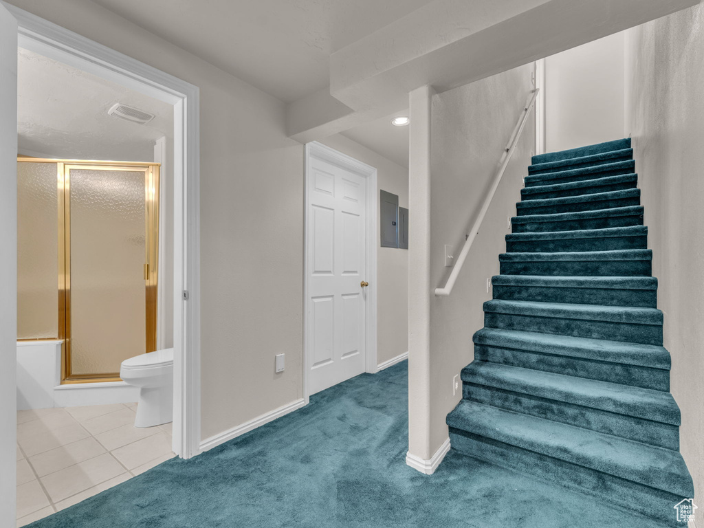 Stairway featuring tile patterned floors, carpet, recessed lighting, baseboards, and electric panel