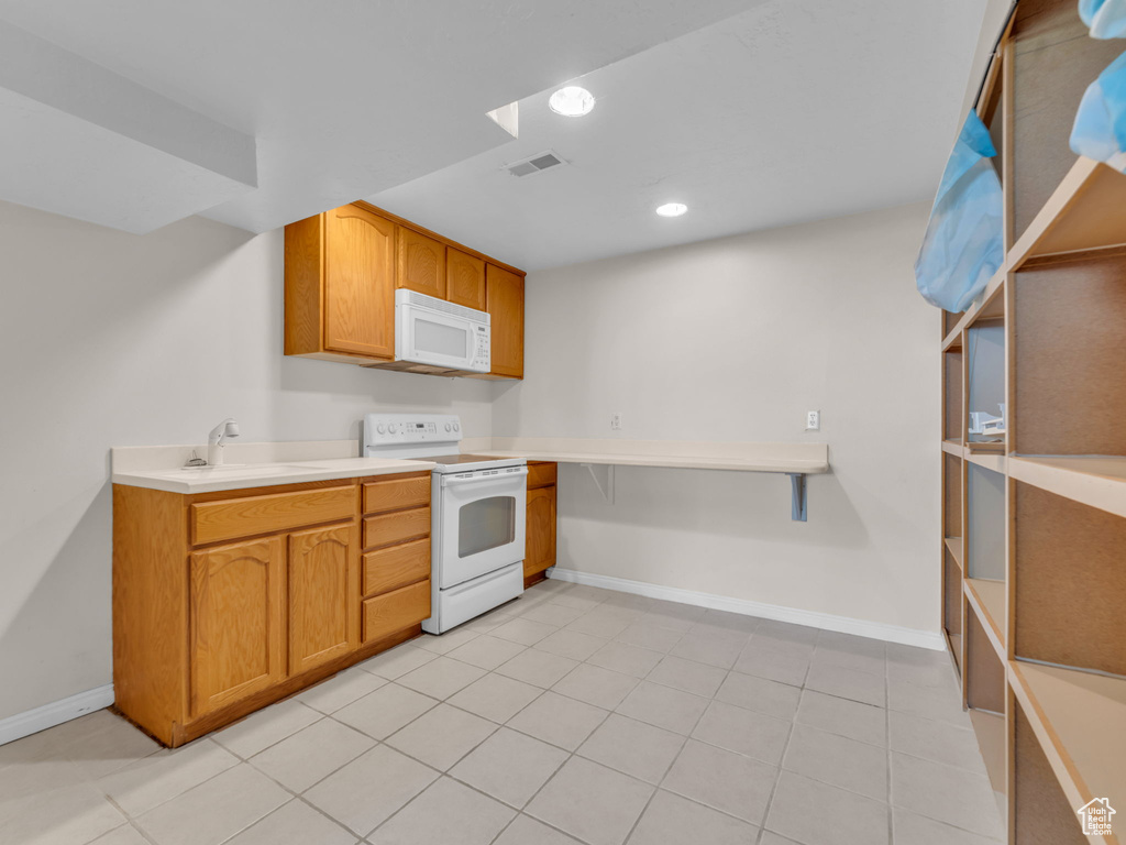 Kitchen featuring white appliances, baseboards, visible vents, and a sink