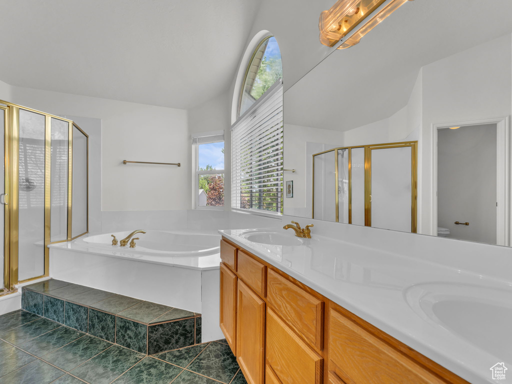 Bathroom with a sink, double vanity, lofted ceiling, a garden tub, and a stall shower