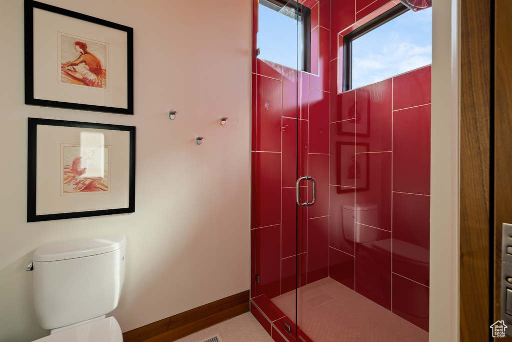 Bathroom featuring a stall shower, toilet, and baseboards