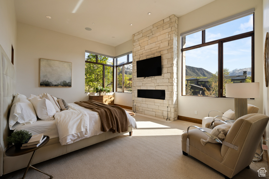 Bedroom featuring carpet flooring, a stone fireplace, and baseboards