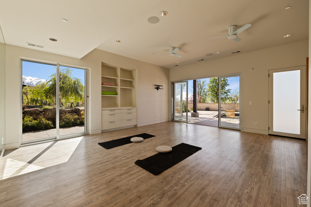Exercise area featuring a ceiling fan, wood finished floors, built in features, and baseboards