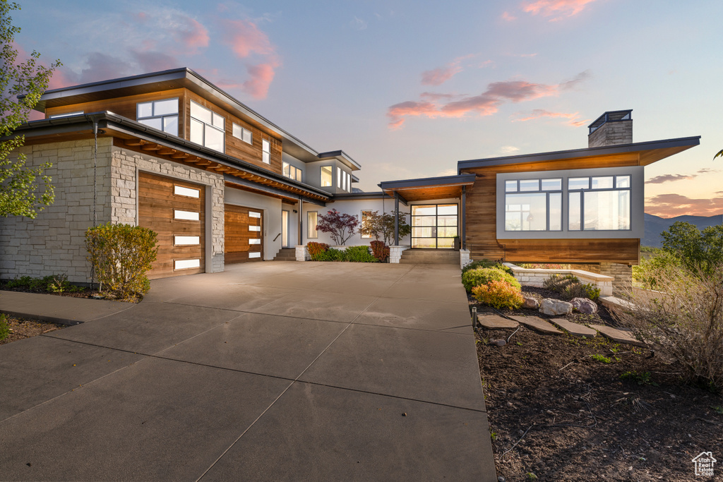 View of front of house featuring concrete driveway, a chimney, and an attached garage