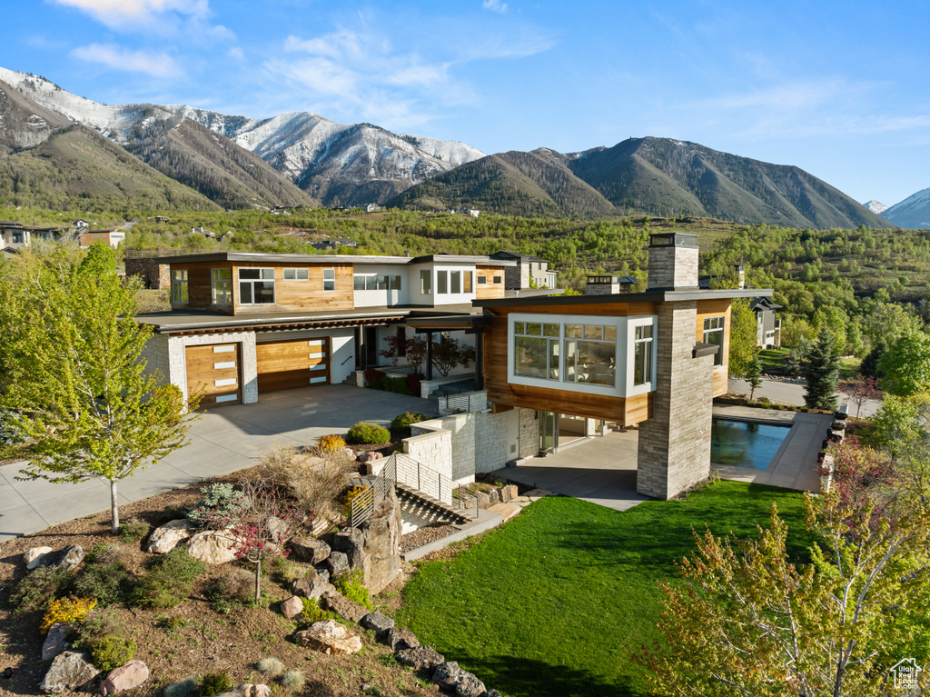Rear view of property with a mountain view, a chimney, and driveway