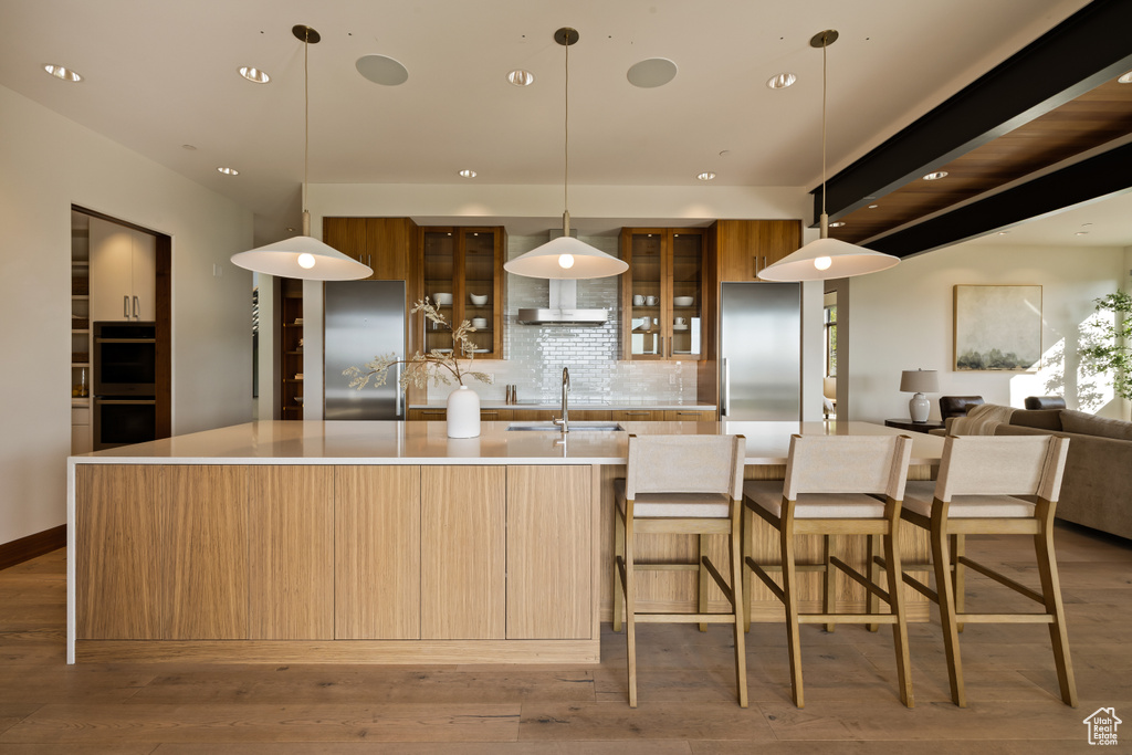 Kitchen featuring modern cabinets, multiple ovens, decorative backsplash, a spacious island, and recessed lighting