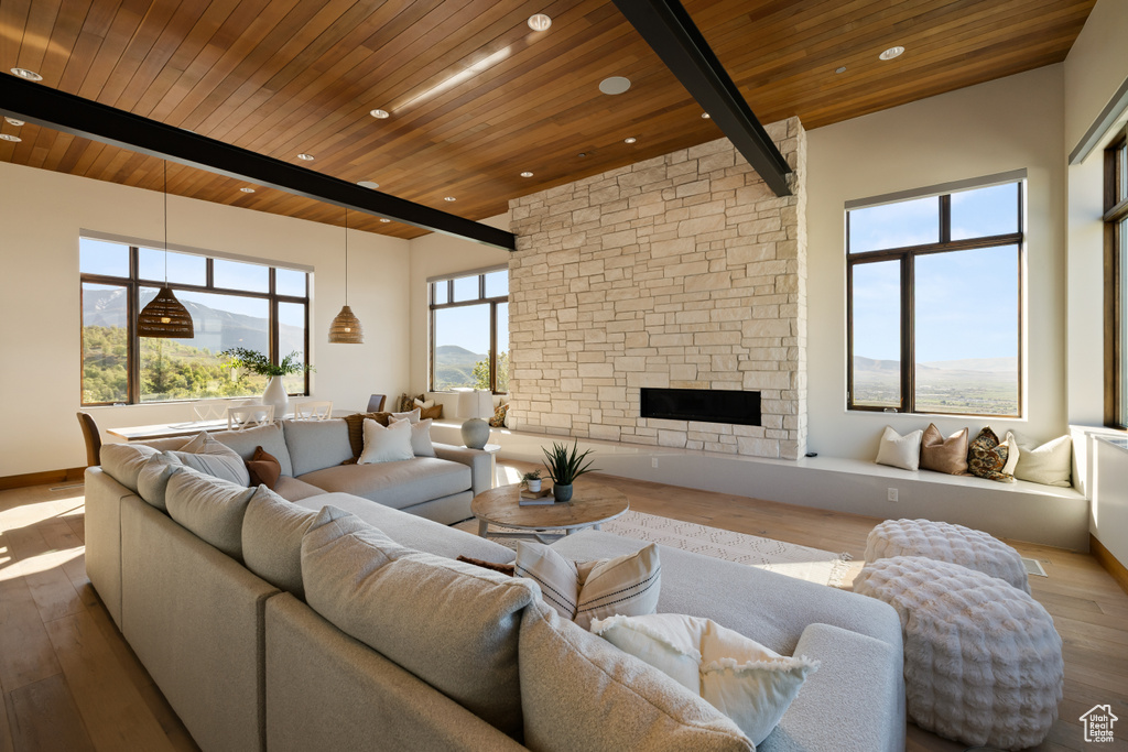 Living room with wood ceiling, wood finished floors, beam ceiling, a stone fireplace, and recessed lighting
