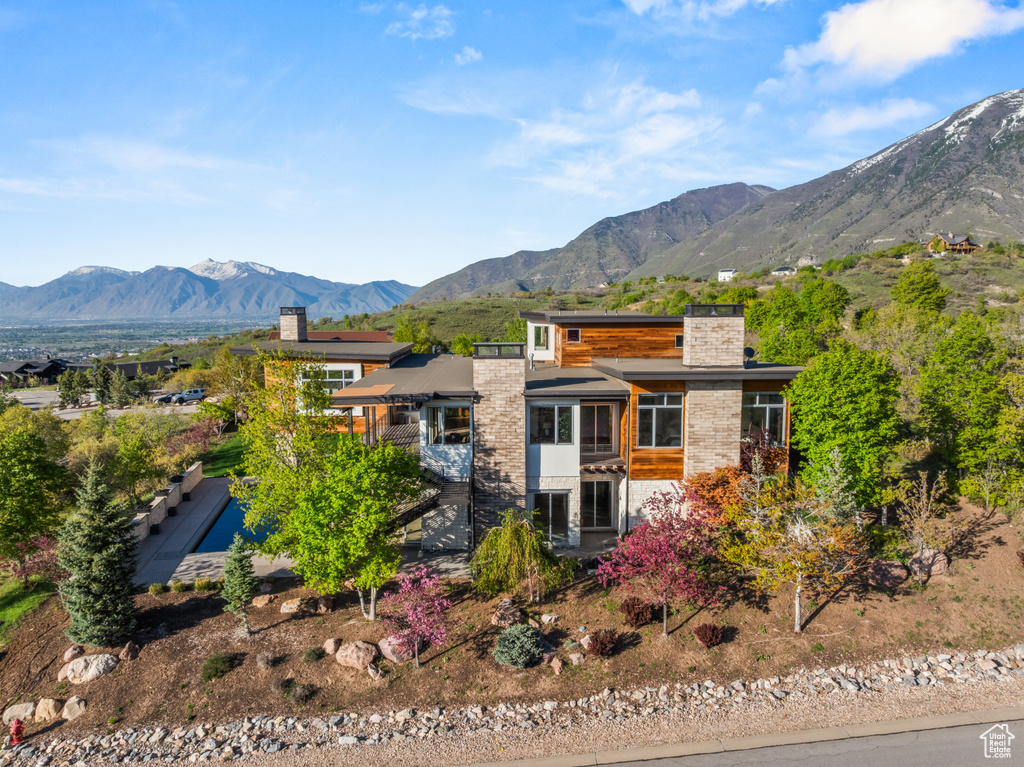 View of front of property with a chimney, a sunroom, and a mountain view