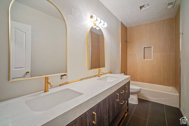 Full bath with double vanity, toilet, tile patterned floors, and a sink