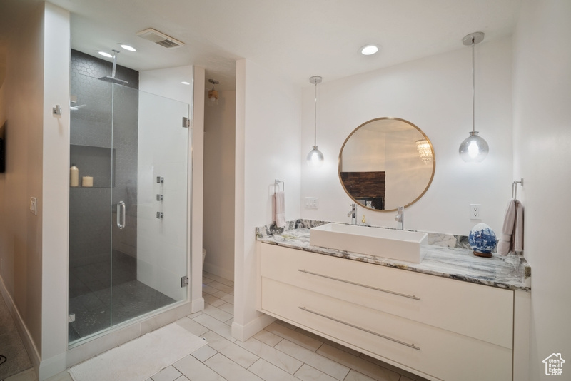 Full bathroom featuring tile patterned flooring, vanity, toilet, a shower stall, and visible vents