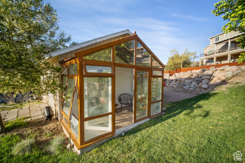 View of outbuilding with fence and a sunroom