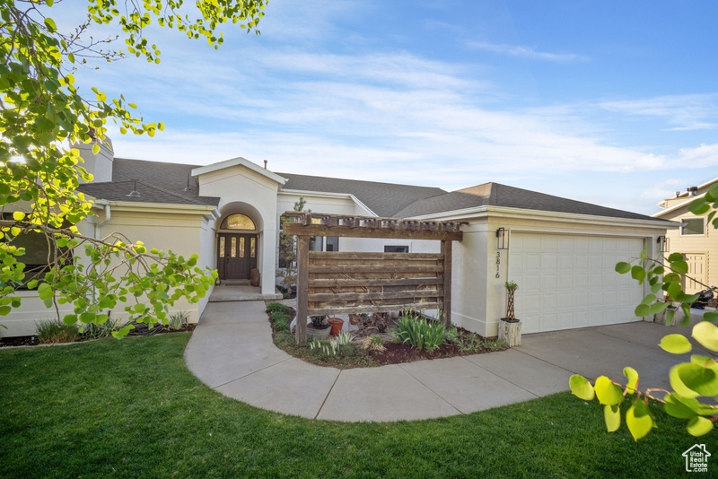 View of front facade with roof with shingles, a front yard, a garage, concrete driveway, and stucco siding