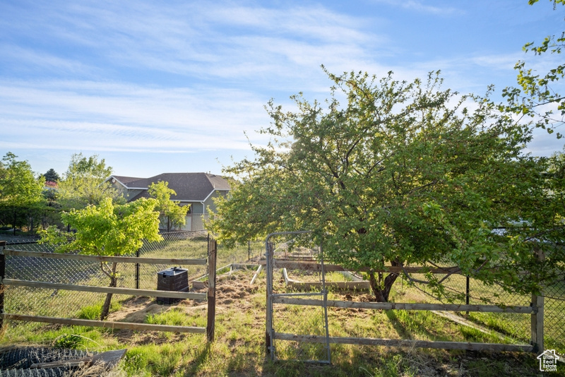 View of yard featuring fence, central AC, and a vegetable garden