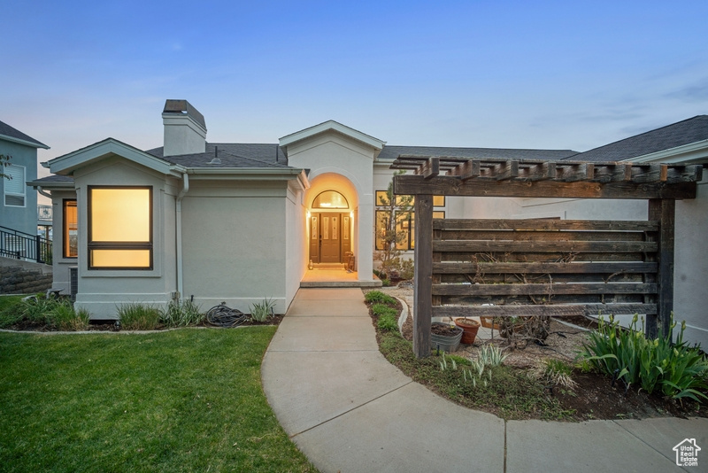View of front of home with a shingled roof, a chimney, a front lawn, and stucco siding