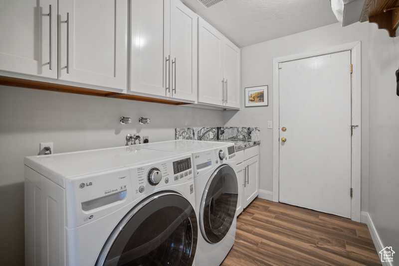 Laundry area with baseboards, dark wood-style flooring, cabinet space, and washing machine and clothes dryer