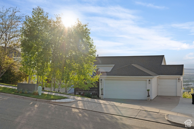 View of front of house featuring an attached garage, a shingled roof, stucco siding, and concrete driveway