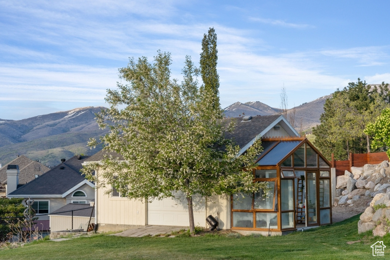 Rear view of house featuring a garage, a mountain view, a yard, and a greenhouse