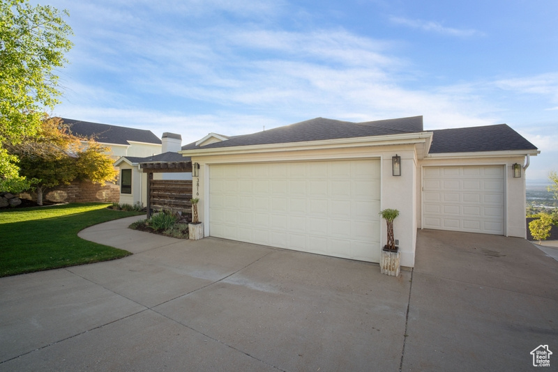 View of front of property featuring driveway, a garage, a front lawn, a shingled roof, and stucco siding