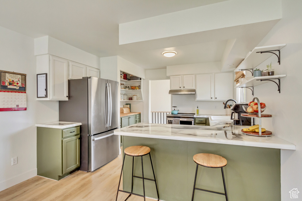 Kitchen with open shelves, light wood-style flooring, stainless steel appliances, a peninsula, and under cabinet range hood