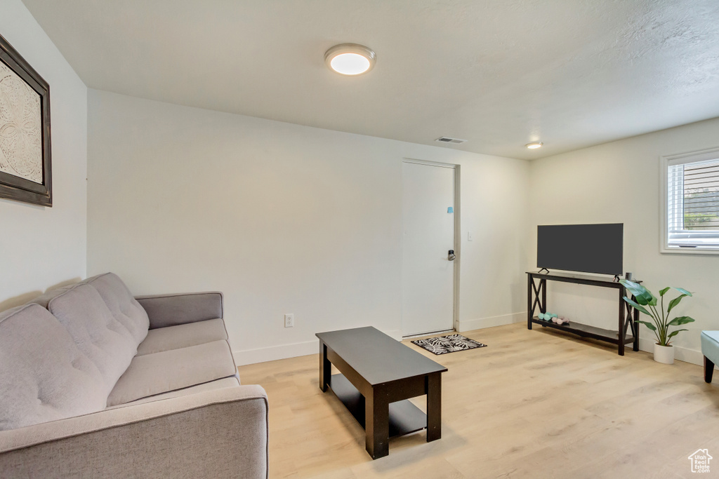 Living room featuring baseboards, light wood-style floors, and visible vents