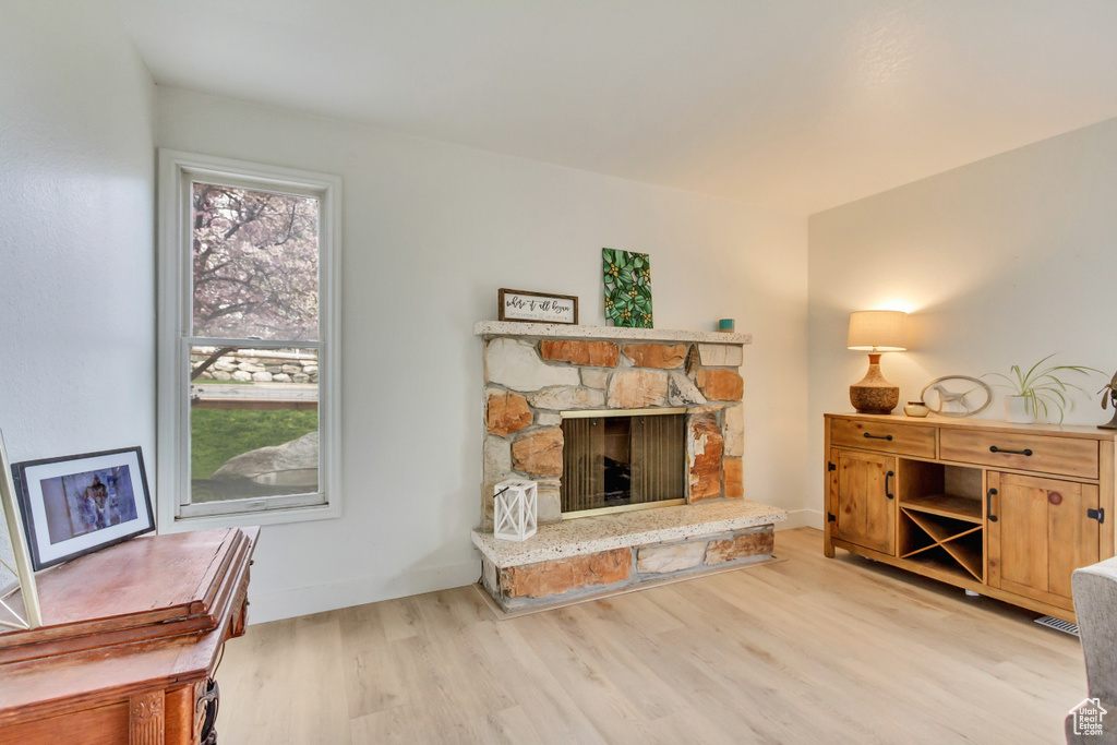 Living room featuring baseboards, a stone fireplace, and wood finished floors