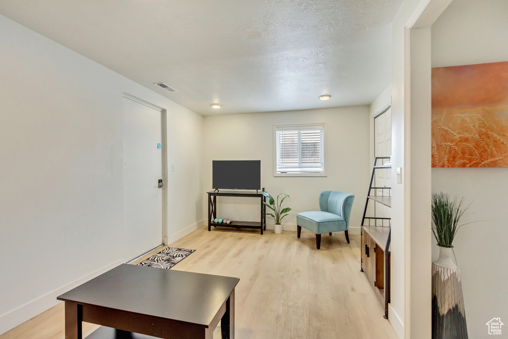 Living area with baseboards, visible vents, and light wood-type flooring