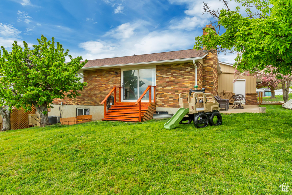 Back of property featuring a chimney, a lawn, a patio area, brick siding, and entry steps