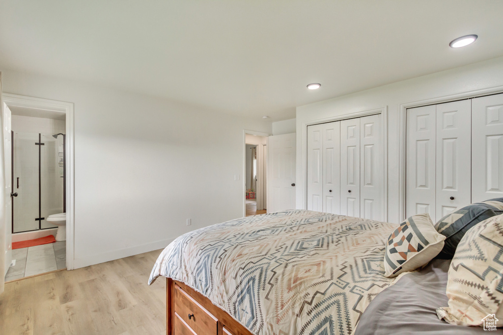 Bedroom featuring ensuite bath, baseboards, two closets, light wood finished floors, and recessed lighting