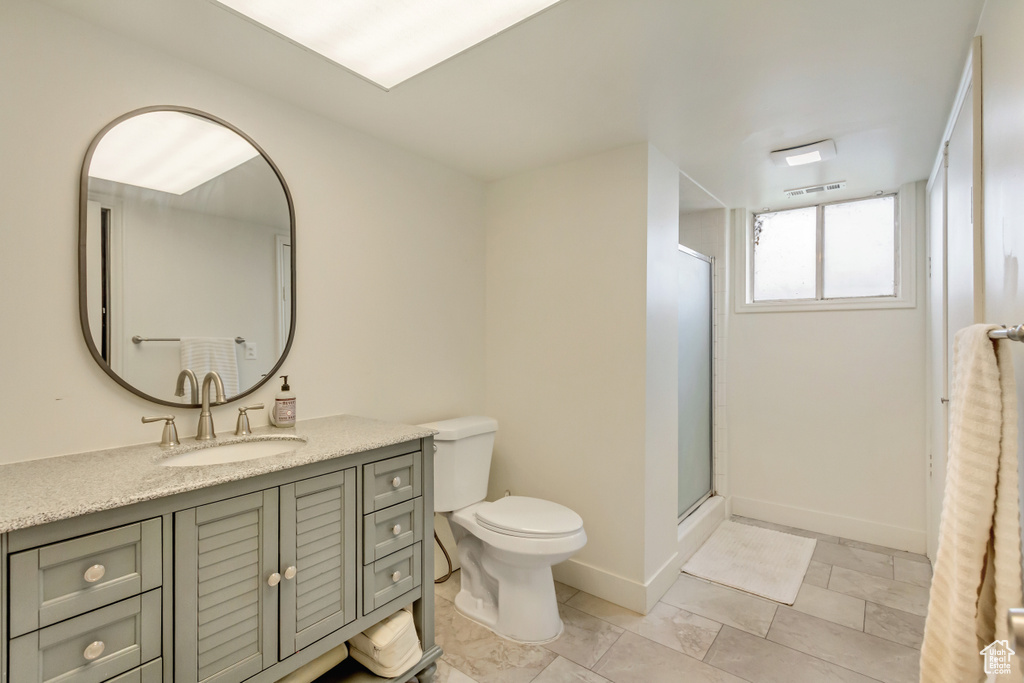 Bathroom featuring vanity, visible vents, toilet, baseboards, and a stall shower